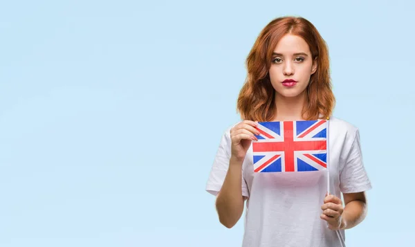 年轻美丽的妇女持有英国国旗在孤立的背景和自信的表情对聪明的面孔认真思考 — 图库照片