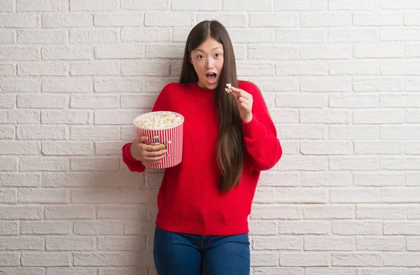 Genç Çinli kadın pop Mısır bir sürpriz yüz, korkuyor ve heyecanlı korku ifadesi ile şok korkmuş yeme tuğla duvarın üzerinden