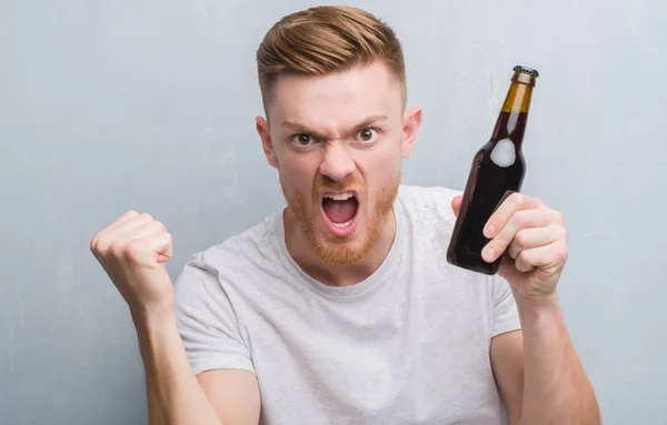 Jovem Ruivo Sobre Parede Grunge Cinza Bebendo Garrafa Cerveja Irritado — Fotografia de Stock