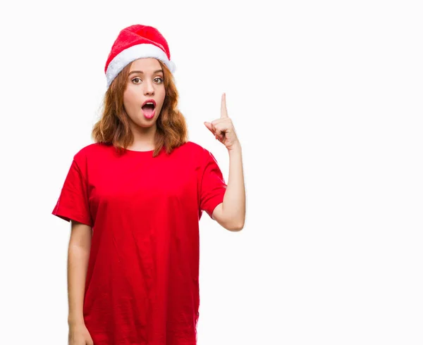 年轻美丽的女人在孤立的背景下戴着圣诞帽指着成功的想法 退出和快乐 第一个 — 图库照片