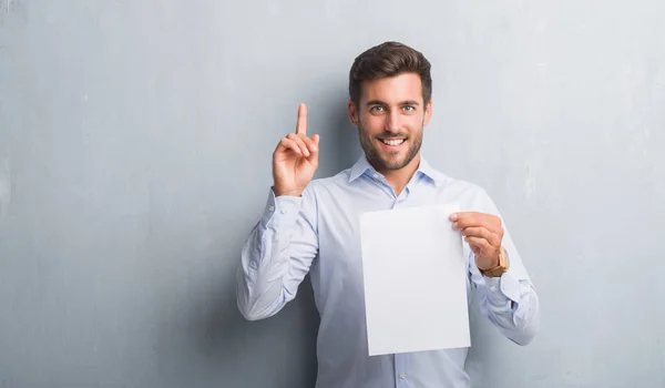 Handsome Young Man Grey Grunge Wall Holding Blank Paper Sheet — Stock Photo, Image