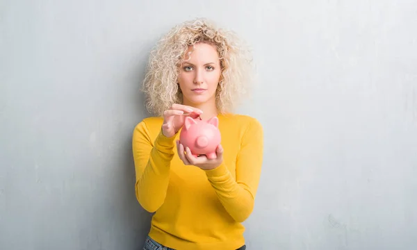 Young Blonde Woman Grunge Grey Background Holding Piggy Bank Confident — Stock Photo, Image