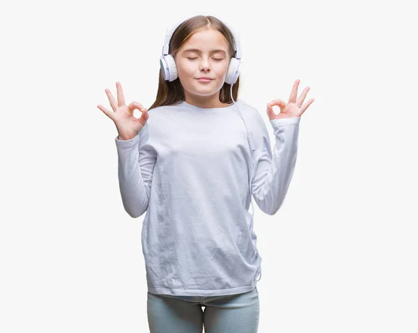年轻美丽的女孩戴着耳机听音乐在孤立的背景下放松和微笑闭上眼睛做冥想手势用手指 瑜伽理念 — 图库照片