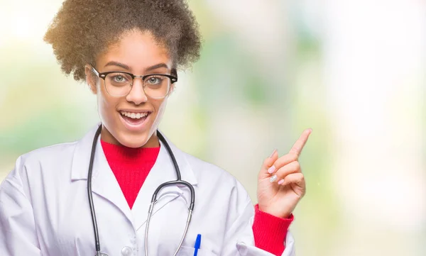 若いアフロ アメリカ人医師女性の顔に大きな笑みを浮かべて隔離された背景にカメラを見ている側の手と指で指す — ストック写真