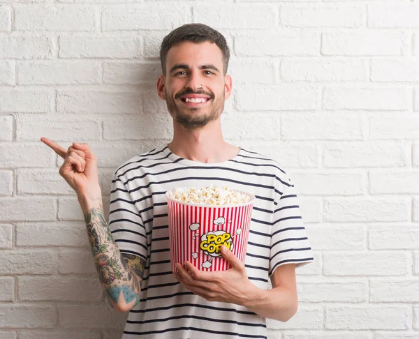 Jonge Volwassen Man Eten Popcorn Staande Witte Bakstenen Muur Zeer — Stockfoto