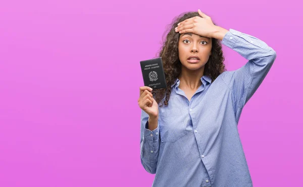 Young hispanic woman holding passport of Italy stressed with hand on head, shocked with shame and surprise face, angry and frustrated. Fear and upset for mistake.