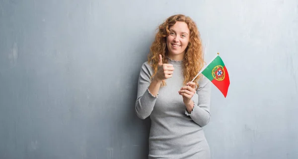 Joven Pelirroja Sobre Gris Grunge Pared Sosteniendo Bandera Portugal Feliz — Foto de Stock