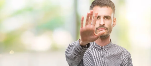 手の手のひらで停止歌ってをしている流行に敏感な若い男 顔に否定的な深刻なジェスチャーで警告式 — ストック写真