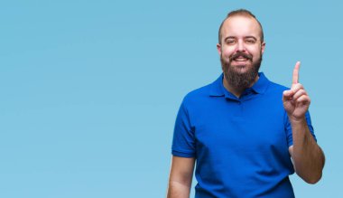 Ve parmak gülümseyen süre bir numara ile kendinden emin ve mutlu yukarıyı gösteren izole arka plan üzerinde mavi gömlek giymiş genç beyaz hipster adam.