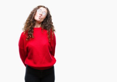 Güzel esmer kıvırcık saçlı Genç kız üzerinde gözlük ve kış kazak giyiyor arka plan yapma balık yüz dudaklı, çılgın ve komik bir jest izole. Komik ifade.