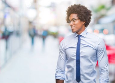 Arka plan uzak tarafına gülümseme ile yüzünde, doğal ifade seyir üzerinde gözlük takan Afro Amerikalı iş adamı izole. Kendine güvenen gülüyor.
