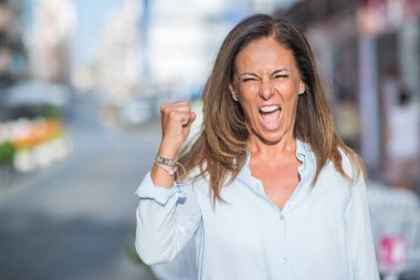 Güzel orta yaş İspanyol kadın güneşli bir günde rahatsız caddenin ve boşa çıkarmak ile öfke, çılgın ve yükseltilmiş eliyle diye bağıran öfke kavramı bağırarak.