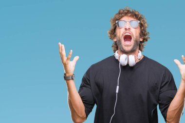 İspanyol yakışıklı üzerinde kulaklık giyen müzik dinlemek arka plan deli izole ve deli bağırarak ve agresif ifade ve silah kaldırdı bağırıyor. Hayal kırıklığı kavramı.