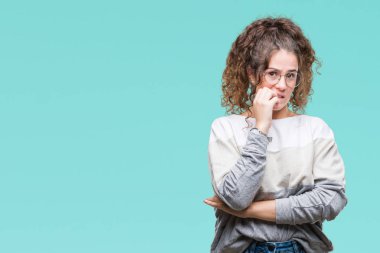 Güzel esmer kıvırcık saçlı Genç kız stresli ve gergin elle çivi ısırma ağzına bakarak izole arka plan üzerinde gözlük takıyorum. Anksiyete sorunu.