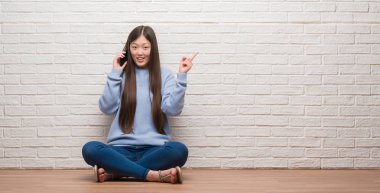 El ve parmak ile tarafına işaret çok mutlu tuğla duvarın üzerinden katta oturan genç Çinli kadın