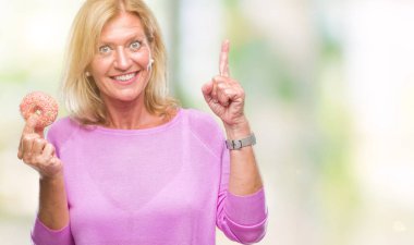 Sarışın kadın üzerinde pembe çörek yeme arka plan bir fikirle sürpriz izole yaş orta veya gülen yüz, bir numara ile işaret parmağı soru