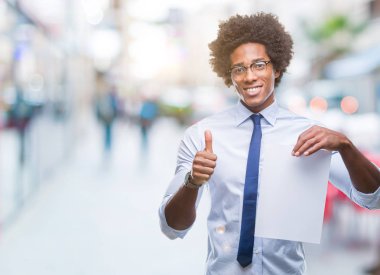 İzole arka plan üzerinde boş kağıt sözleşme ok işareti, başparmak ile parmak, mükemmel işareti yapıyor kocaman bir gülümseme ile mutlu tutarak Afro Amerikalı adam