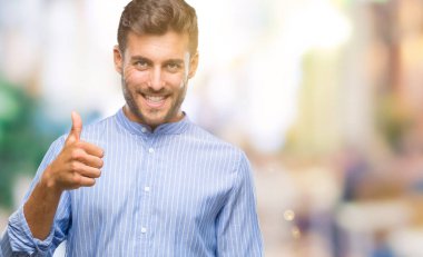 Yakışıklı delikanlı hareketi el ile mutlu yaşasın yapıyor izole arka plan üzerinde. Kameraya bakarak başarı gösteren ile ifade onaylama.