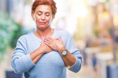 Atrractive üst düzey beyaz Kızıl saçlı kadın kapalı gözler ile göğüs ellerinde ve yüzünde minnettar jest ile gülümseyen izole arka plan yüzünden. Sağlık kavramı.