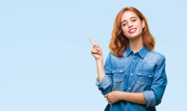 Kameraya bakarak yan el ve parmak ile işaret izole arka yüzünde kocaman bir gülümseme ile genç güzel kadın.