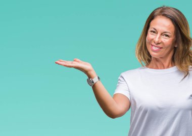 Orta yaş neşeli sunulması ve kameraya bakarak avucunun ile işaret gülümseyen izole arka plan üzerine İspanyol kadın kıdemli.