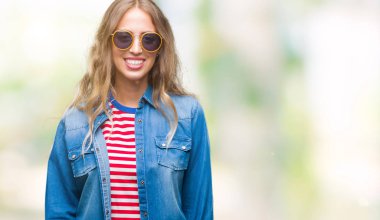 Yüzünde mutlu ve güzel bir gülümseme ile izole arka plan üzerinde güneş gözlüğü takıyor güzel sarışın genç kadın. Şanslı kişi.