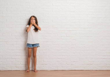 Genç İspanyol çocuğun stading beyaz tuğla duvar eller için hata ile ağız kapsayan şok içinde. Gizli kavramı.