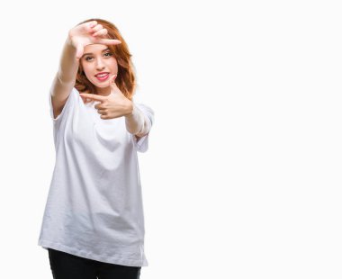 Genç güzel kadın elle yapma çerçeve ve parmakları ile mutlu yüz gülümseyen izole arka plan yüzünden. Yaratıcılık ve Fotoğrafçılık kavramı.