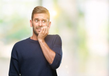 Genç yakışıklı adam stresli ve gergin ile izole arka plan üzerinde kış kazak giyen tırnak ısırma dudaklarından eller. Anksiyete sorunu.