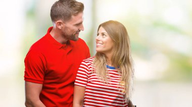 Uzak tarafına yüzünde, doğal ifade gülümseme ile seyir izole arka plan üzerinde aşık genç bir çift. Kendine güvenen gülüyor.