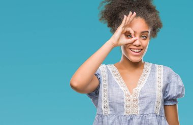 Genç afro Amerikalı kadın gülümsüyor, parmakları ile mutlu yüz üzerinden seyir göz el ile ok jest yapıyor izole arka plan üzerinde.