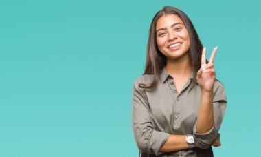 Genç güzel Arap kadın mutlu yüz zafer işareti yaparken kameraya göz kırpıyor ile gülümseyen izole arka plan yüzünden. İki numaralı.