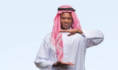 Geleneksel keffiyeh ile büyük ve büyük boy işaret, ölçü birimi sembol gösteren el eller izole arka plan üzerinde giyen genç Arapça Afrika adam. Kameraya bakarak gülümsüyordu. Ölçüm kavramı.