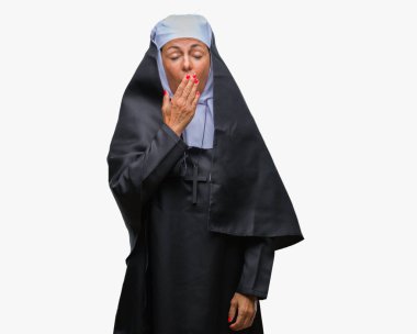 Orta yaş üst düzey Hıristiyan Katolik Rahibe kadın izole arka plan üzerinde el ile ağız kapsayan yorgun esneme sıkılmış. Restless ve uyku hali.