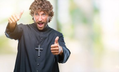Yakışıklı İspanyol Katolik rahip adam el ile pozitif jest yapıyor onaylama izole arka plan üzerinde başparmak gülümseyen ve başarı için mutlu. Kamera, kazanan jest arıyorsunuz.