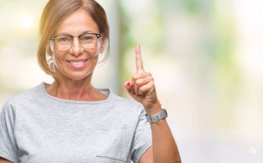 Başarılı fikirle izole arka plan işaret parmağı üzerinde gözlük takan orta yaş İspanyol kadın kıdemli. Çıktıktan ve mutlu. Bir numara.