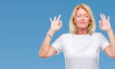 Orta yaş sarışın kadın izole arka plan üzerinde dinlenmek ve gülümseyen gözlerle parmak ile meditasyon jest yapıyor kapalı. Yoga kavramı.