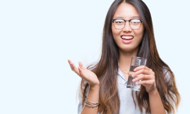 Genç Asyalı kadın büyük gülümseme ile çığlık zaferini kutluyor ve ellerini kaldırdı izole arka plan çok mutlu ve heyecanlı, kazanan ifade bir bardak su içme