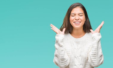 Üzerinde kış kazak giyen genç güzel Arap kadın deli ve çılgın çığlık kaldırdı ve kapalı gözleri heyecanlı silah ile başarı için arka plan kutlama izole. Kazanan kavramı