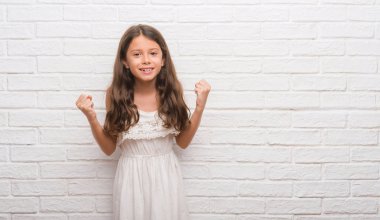 Beyaz tuğla duvar kutluyor üzerinde genç İspanyol çocuğun şaşırttı ve başarı için kaldırdı kollarını açarak hayret ve gözleri açık. Kazanan kavramı.