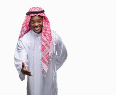 Geleneksel keffiyeh dostu sunan karşılıklı tebrik ve davet edici gülümseyen izole arka plan üzerinde giyen genç Arapça Afrika adam. Başarılı iş.