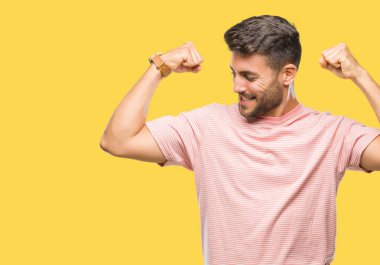 Yakışıklı genç gururlu gülümseyen kol kasları gösterilen izole arka plan üzerinde. Fitness kavramı.