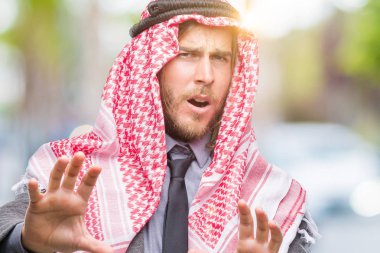 Uzun saçlı keffiyeh üzerinde giyen genç yakışıklı Arap adam arka plan korkuyor ve korku ifade dur hareketi el ile ile dehşete şokta bağırarak izole. Panik kavramı.