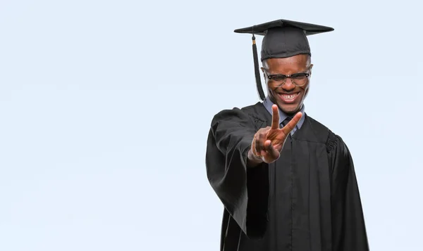 ヤングは 勝利のサインをやって指を表示するカメラを笑みを浮かべて隔離された背景にアフリカ系アメリカ人を卒業しました — ストック写真