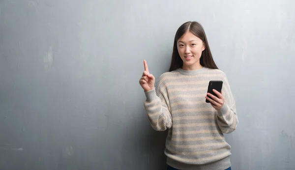 Jovem Chinesa Sobre Parede Cinza Olhando Para Smartphone Surpreso Com — Fotografia de Stock