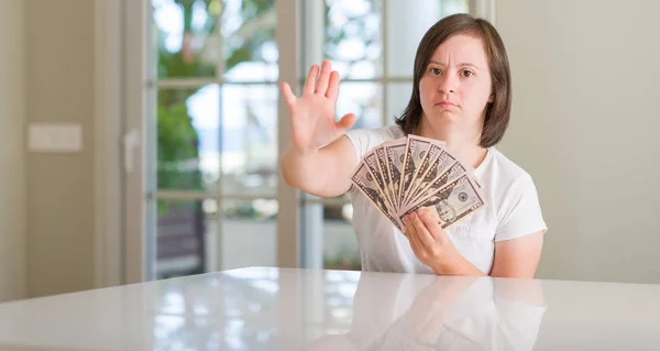 唐氏综合征妇女在家里拿着钱张开手做停止标志认真和自信的表达 防御姿态 — 图库照片