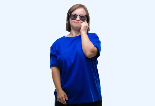 有唐氏综合症的年轻成年妇女戴着太阳镜在与世隔绝的背景下 用手咬着钉子 神情紧张 神经质 焦虑问题 — 图库照片
