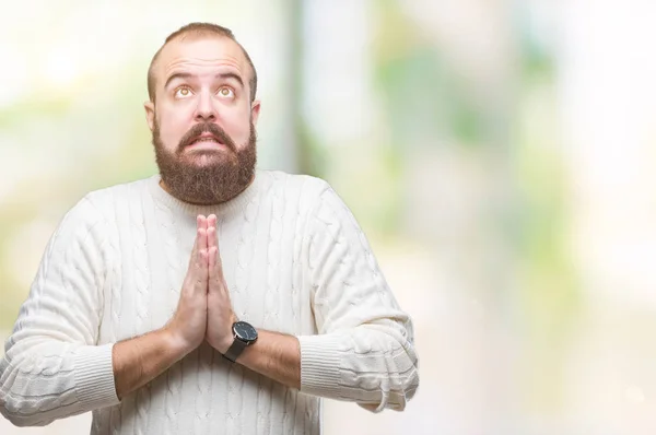 Young caucasian hipster man wearing winter sweater over isolated background begging and praying with hands together with hope expression on face very emotional and worried. Asking for forgiveness. Religion concept.