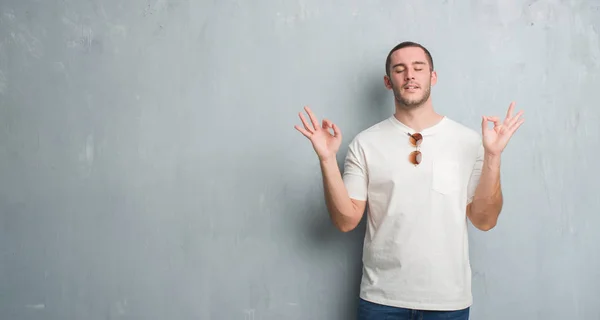 Joven Caucásico Hombre Sobre Gris Grunge Pared Usando Gafas Sol — Foto de Stock