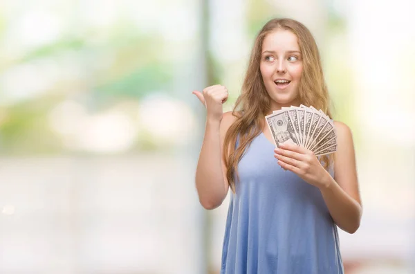 Joven Mujer Rubia Sosteniendo Dólares Señalando Mostrando Con Pulgar Hacia — Foto de Stock